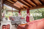 Sun-drenched conservatory with stunning mountain views, featuring comfortable sofas and a wooden beamed ceiling.