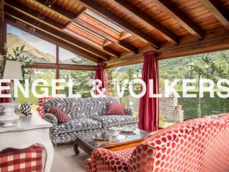 Sun-drenched conservatory with stunning mountain views, featuring comfortable sofas and a wooden beamed ceiling.