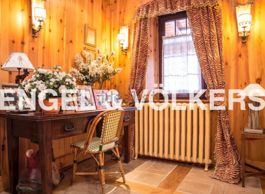Charming wooden-paneled room with antique desk and chair, creating a cozy and inviting atmosphere.