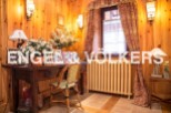 Charming wooden-paneled room with antique desk and chair, creating a cozy and inviting atmosphere.