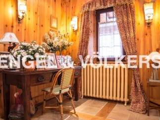 Charming wooden-paneled room with antique desk and chair, creating a cozy and inviting atmosphere.