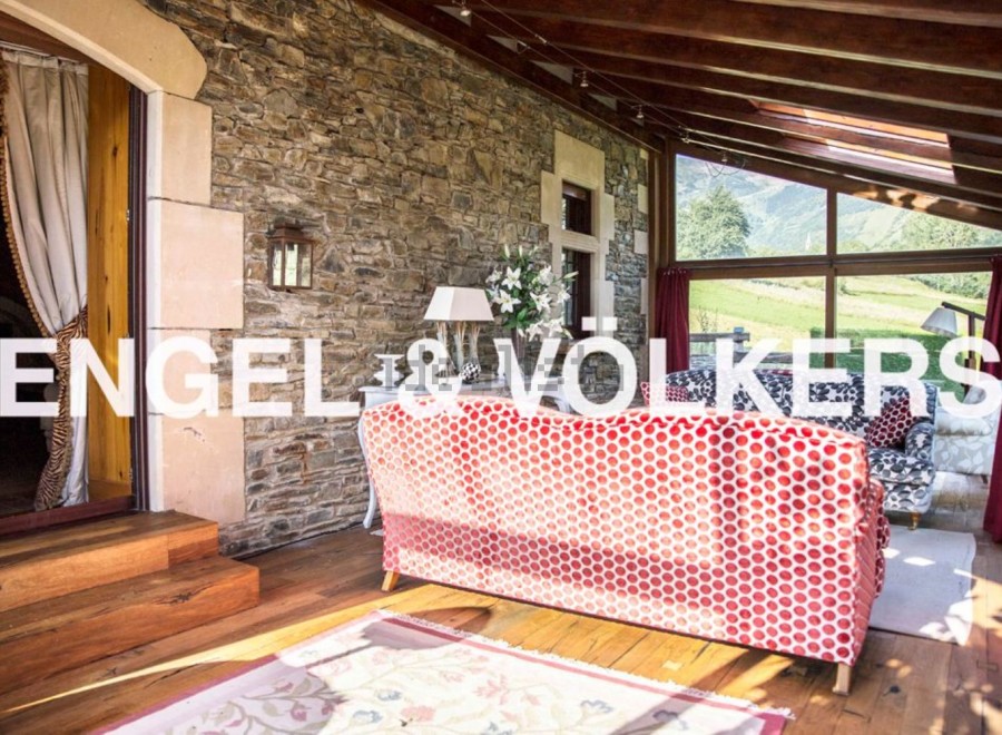 Sun-drenched solarium with stunning mountain views, featuring a cozy red sofa and hardwood floors.