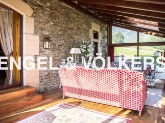 Sun-drenched solarium with stunning mountain views, featuring a cozy red sofa and hardwood floors.