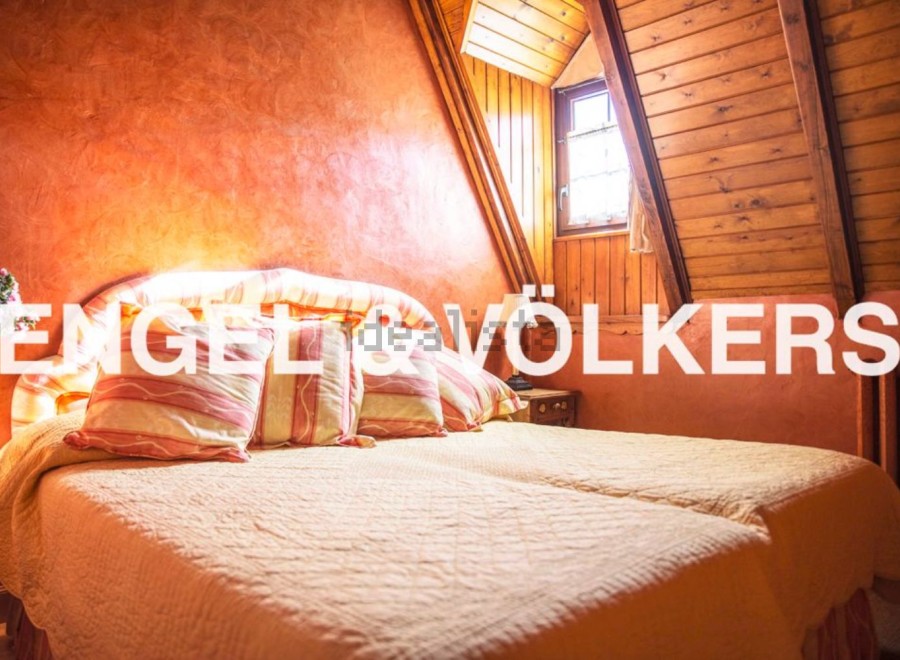 Cosy attic bedroom with wooden beams and orange walls.