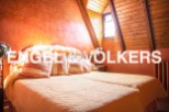 Cosy attic bedroom with wooden beams and orange walls.
