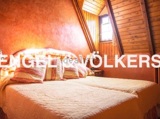 Cosy attic bedroom with wooden beams and orange walls.