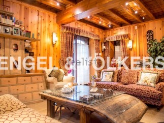 This stunning chalet boasts a warm and inviting living area, complete with wood paneling and exposed beams.
