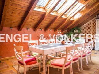 Charming attic dining area with wooden beams and skylights, creating a bright and airy atmosphere.