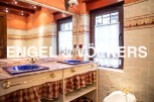 Charming bathroom with double sinks, checkered valance, and vintage-style fixtures.