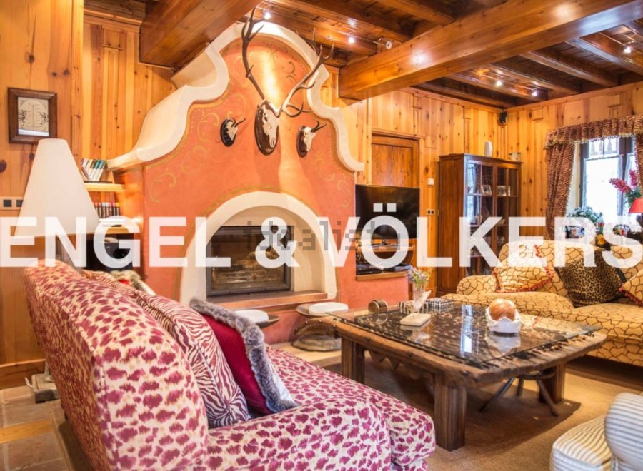 This stunning chalet boasts a spacious living area with a large, ornate fireplace as the centerpiece.