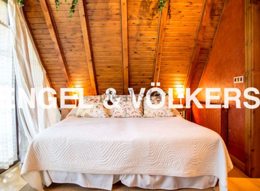 Cosy attic bedroom with wooden beams and large bed.