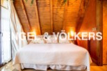 Cosy attic bedroom with wooden beams and large bed.