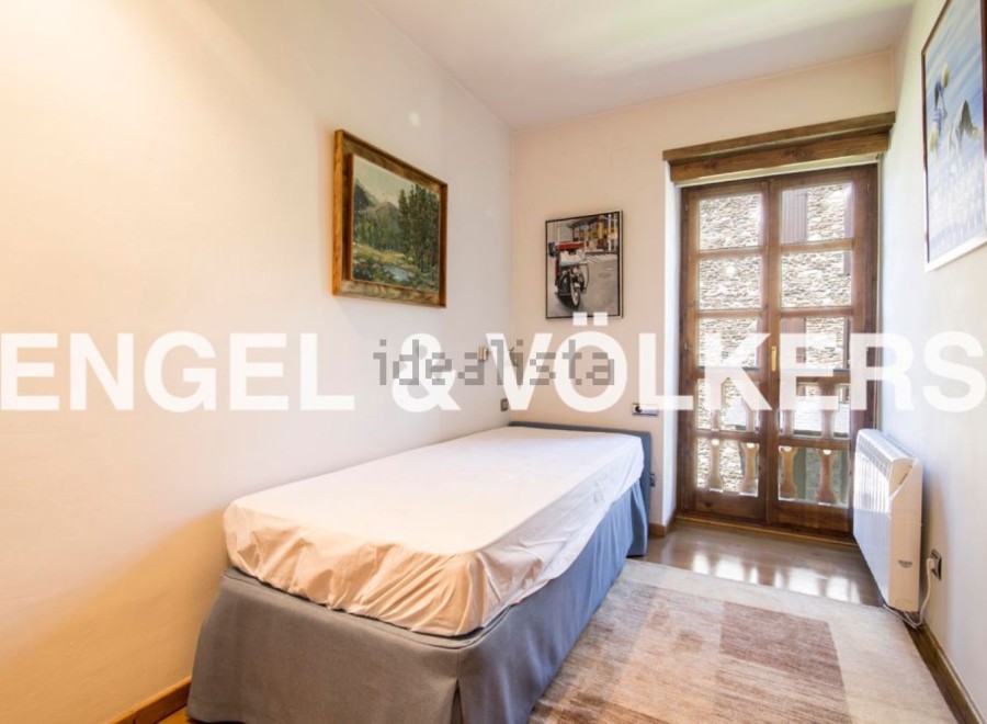 Cozy bedroom with single bed, offering tranquil views through a charming wooden door.