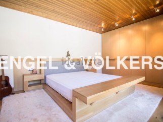 This stunning bedroom boasts a minimalist design with a light oak platform bed and built-in wooden wardrobes.