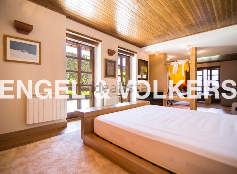 This stunning property boasts a spacious bedroom with large windows offering breathtaking views, a modern wooden bed frame, and a cozy atmosphere.