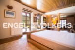 This stunning property boasts a spacious bedroom with large windows offering breathtaking views, a modern wooden bed frame, and a cozy atmosphere.
