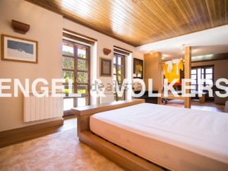 This stunning property boasts a spacious bedroom with large windows offering breathtaking views, a modern wooden bed frame, and a cozy atmosphere.
