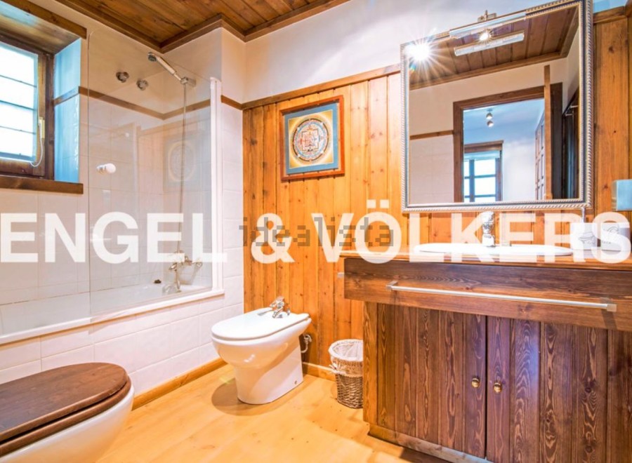 This charming bathroom boasts a rustic wooden vanity and a spacious shower, creating a warm and inviting atmosphere.
