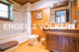 This charming bathroom boasts a rustic wooden vanity and a spacious shower, creating a warm and inviting atmosphere.