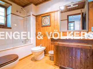This charming bathroom boasts a rustic wooden vanity and a spacious shower, creating a warm and inviting atmosphere.