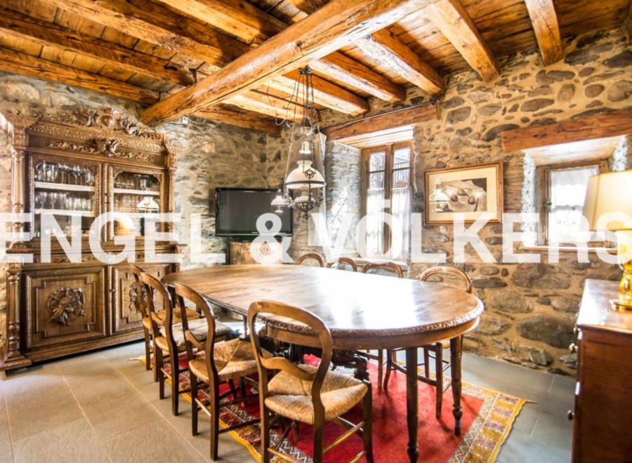 This stunning property boasts a spacious dining room with a large antique wooden table, surrounded by rustic chairs and a beautiful oriental rug.