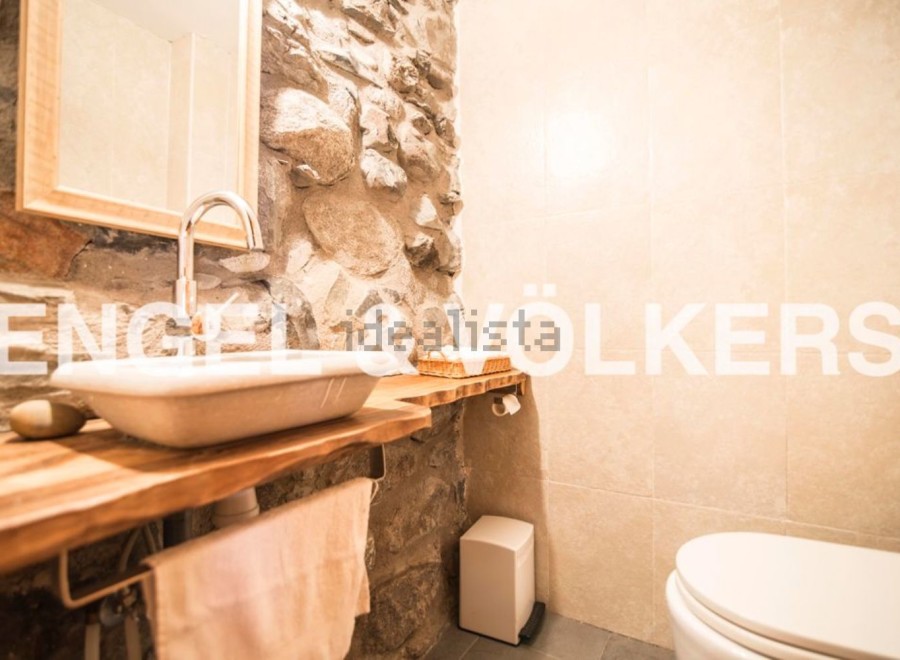 Rustic bathroom with stone wall and wooden vanity.