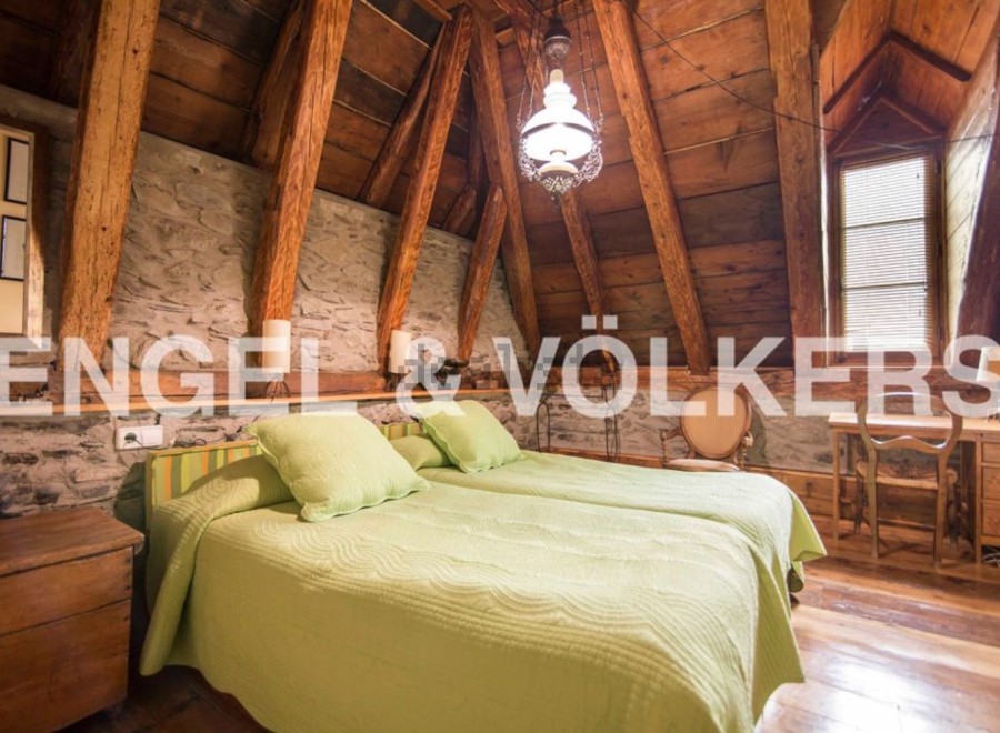 Cosy attic bedroom with exposed wooden beams and stone walls.