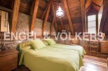 Cosy attic bedroom with exposed wooden beams and stone walls.