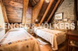 Charming rustic attic bedroom with exposed wooden beams and stone walls.