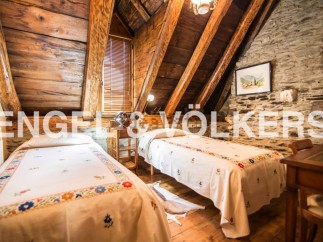 Charming rustic attic bedroom with exposed wooden beams and stone walls.