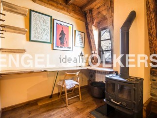 Charming attic room with wooden beams, featuring a built-in desk and a wood-burning stove.