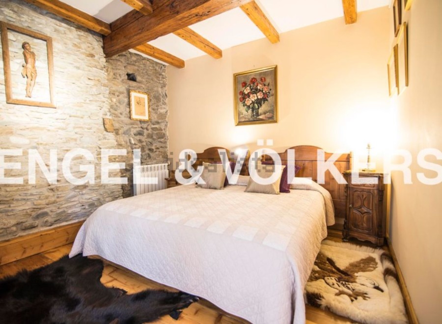 Cosy bedroom with stone walls and wooden beams, offering a rustic charm.