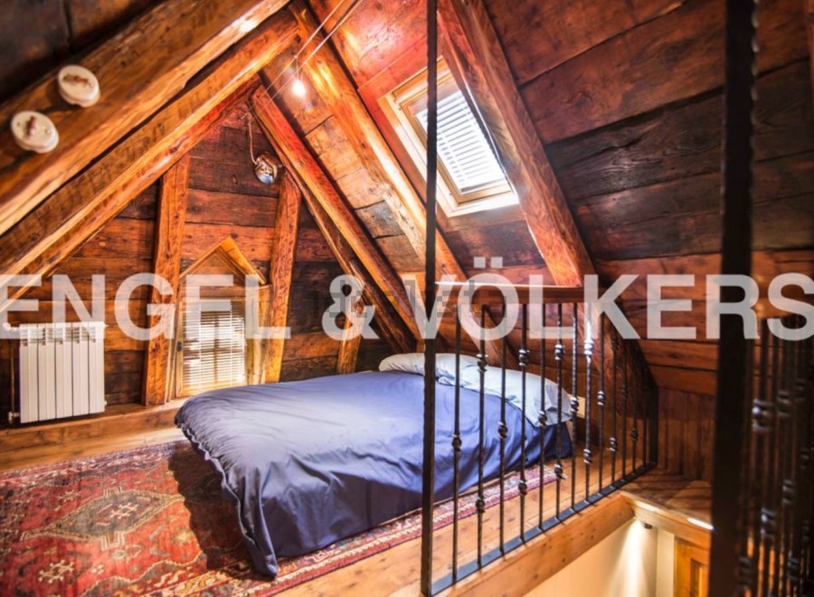 Charming attic bedroom with exposed wooden beams and skylight.