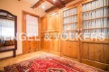 This charming bedroom boasts beautiful wooden built-in wardrobes with glass panel doors and curtains, offering ample storage space.