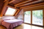 Cozy attic bedroom with wooden beams and large windows offering stunning views.