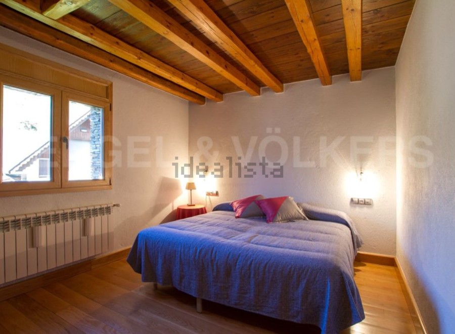 Cozy bedroom with wooden beams and hardwood floors.