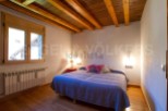 Cozy bedroom with wooden beams and hardwood floors.