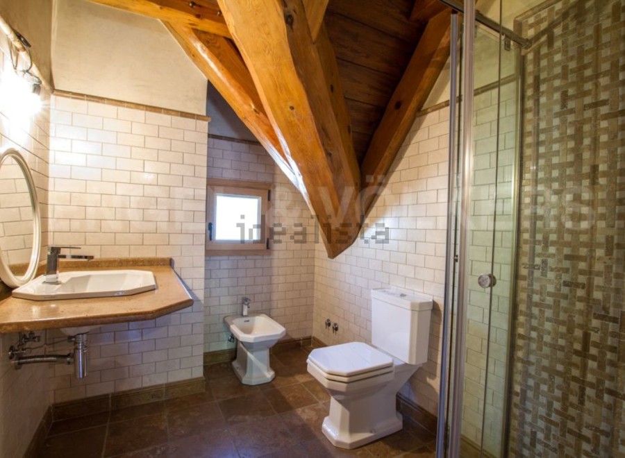 Charming bathroom with rustic wooden beams and tiled walls.