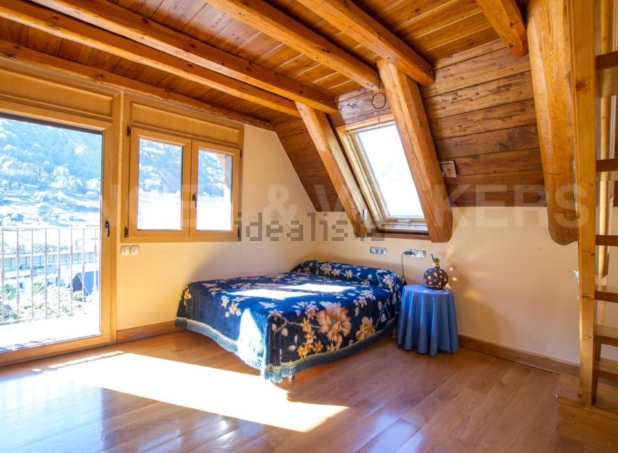 Cozy attic bedroom with wooden beams and stunning mountain views.