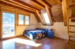 Cozy attic bedroom with wooden beams and stunning mountain views.