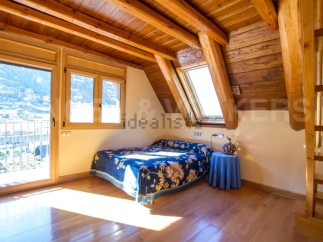 Cozy attic bedroom with wooden beams and stunning mountain views.