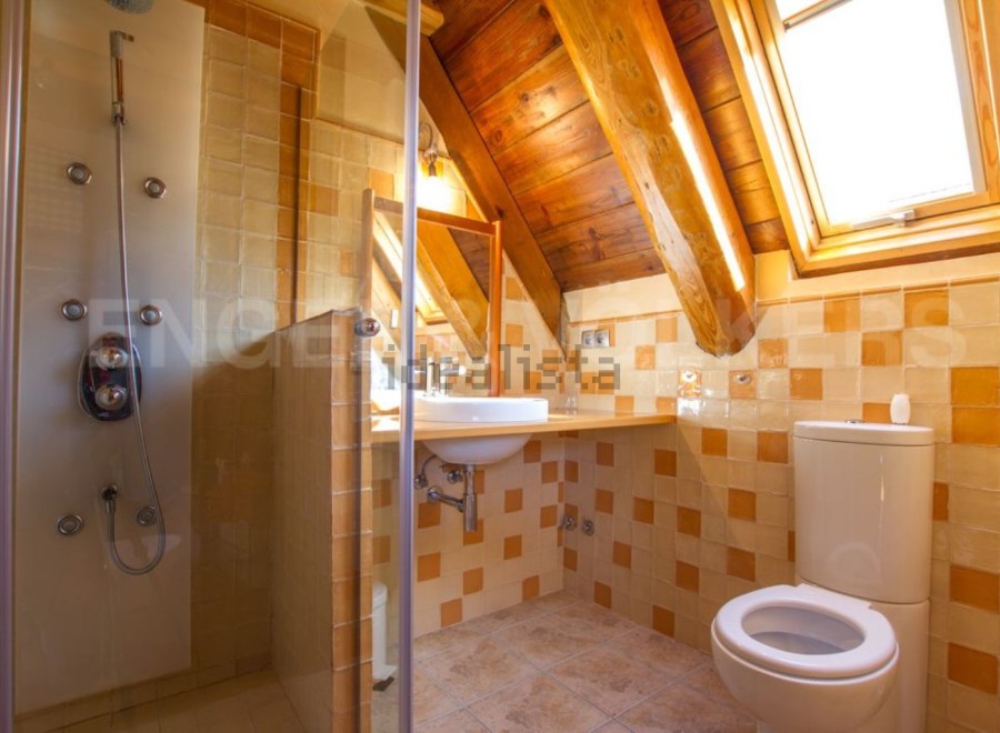 Charming attic bathroom with wooden beams, skylight, and a walk-in shower.