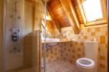 Charming attic bathroom with wooden beams, skylight, and a walk-in shower.