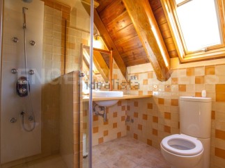 Charming attic bathroom with wooden beams, skylight, and a walk-in shower.