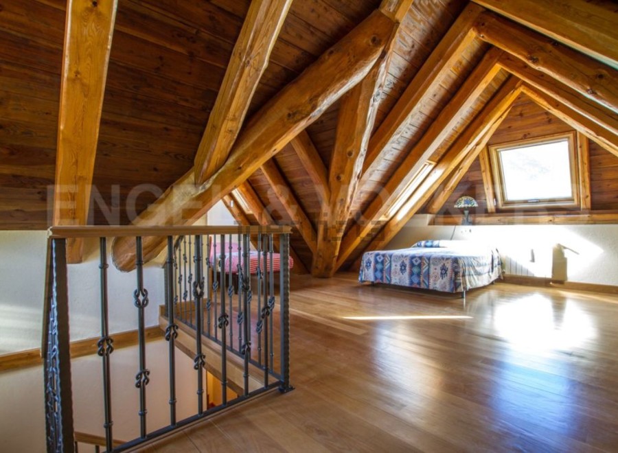 This stunning attic bedroom boasts a beautiful wooden beam ceiling and hardwood floors.