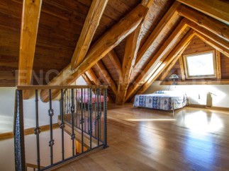 This stunning attic bedroom boasts a beautiful wooden beam ceiling and hardwood floors.