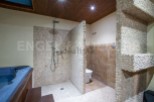 This luxurious bathroom boasts a spacious shower with pebble tile walls, a modern toilet, and a built-in jacuzzi tub.