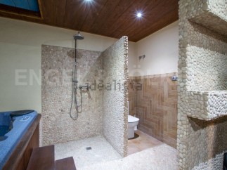 This luxurious bathroom boasts a spacious shower with pebble tile walls, a modern toilet, and a built-in jacuzzi tub.