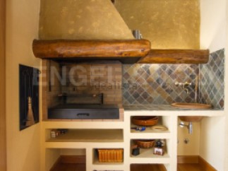 This stunning property boasts a built-in outdoor kitchen, complete with a traditional wood-fired grill and ample storage.