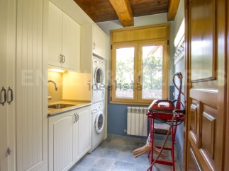 This stunning laundry room boasts custom cream cabinets, a built-in sink, and high-end washer and dryer.